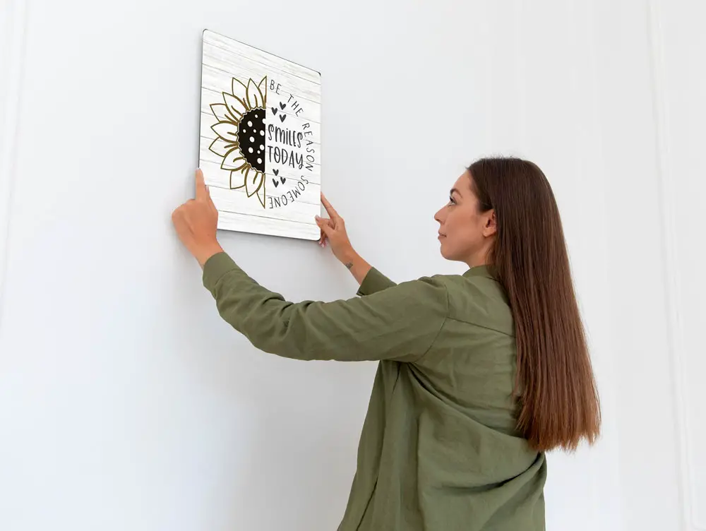 female holding a metal sign against a blank white wall