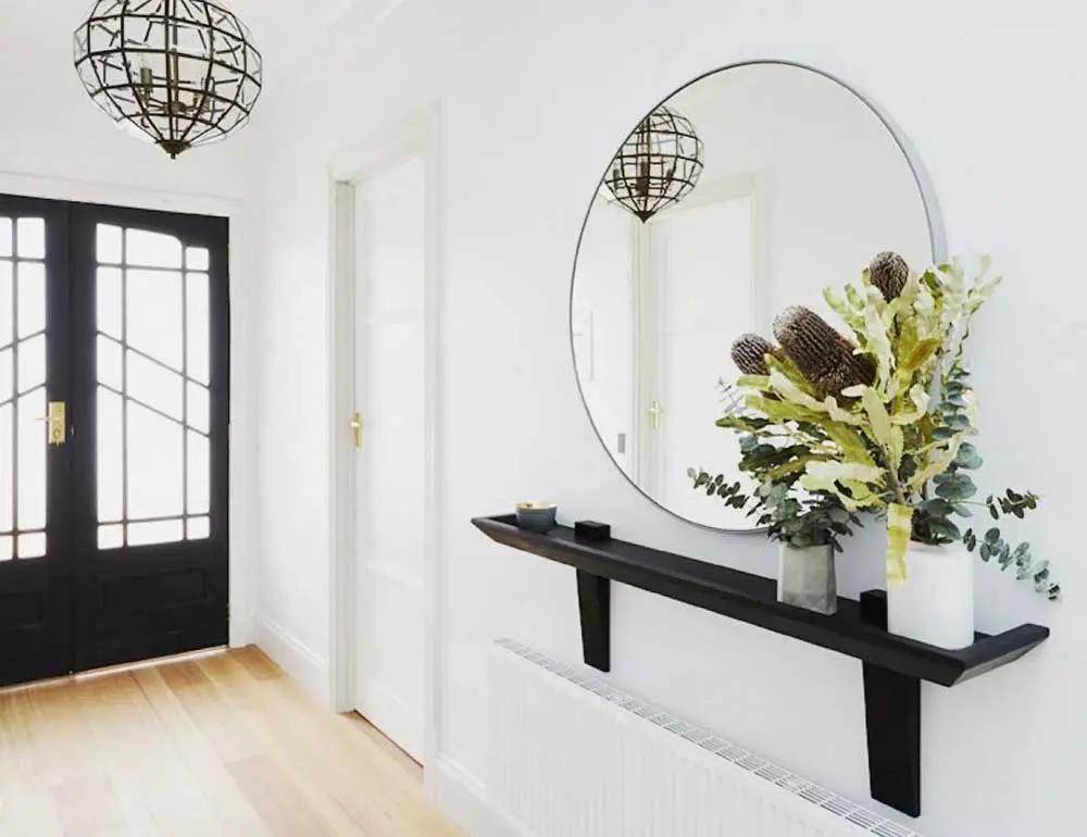 round mirror in white hallway